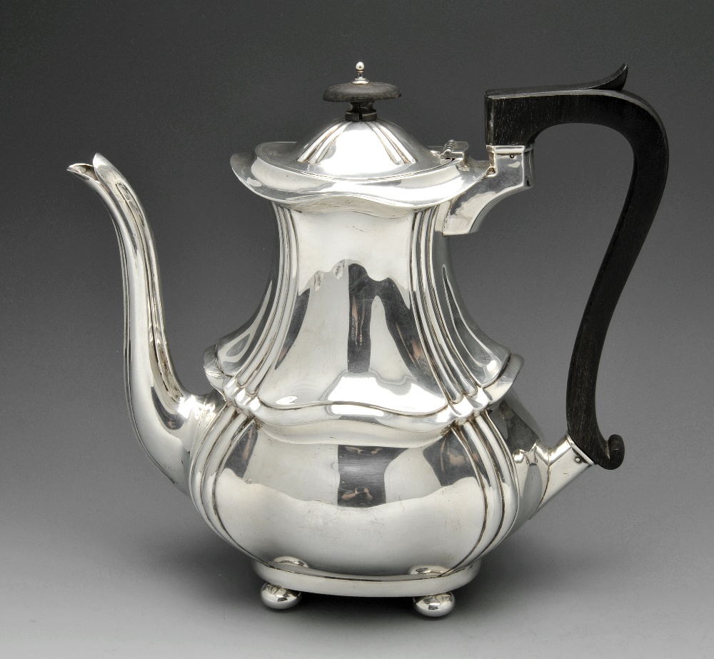 An Edwardian silver coffee pot of bulbous fluted form with ebonised handle and finial and standing