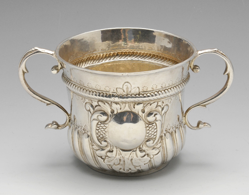 A George I silver porringer, the typical form with fluted lower body rising to the foliate scroll