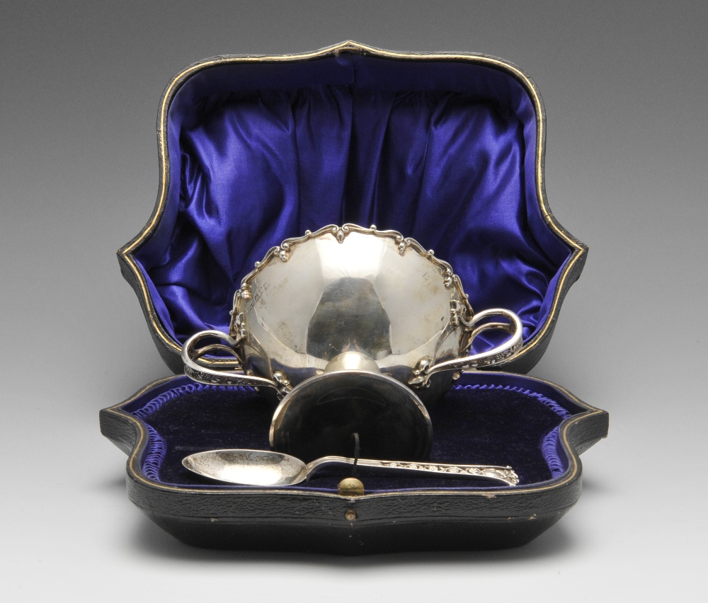 An early twentieth century Irish cased silver bowl and spoon, the conical bowl with applied scroll