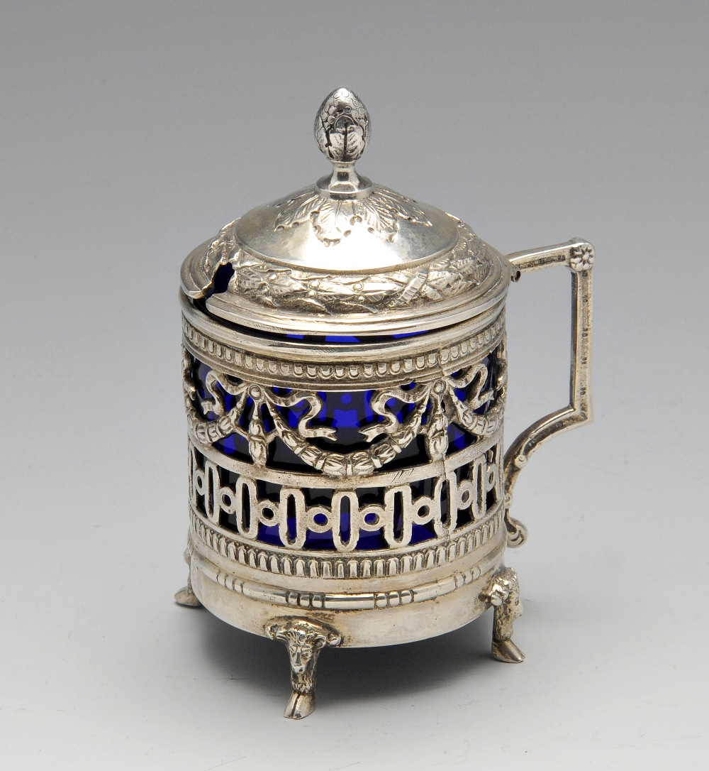 A German silver mustard pot with blue glass liner, having ribbon and garland swag piercing above