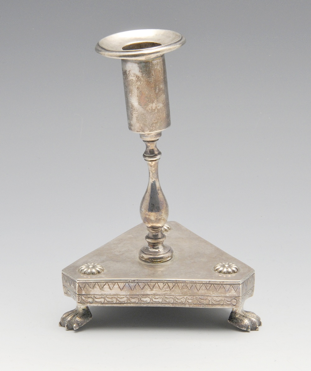 A South American candlestick of tri-form, florally embellished base raised on three paw feet and