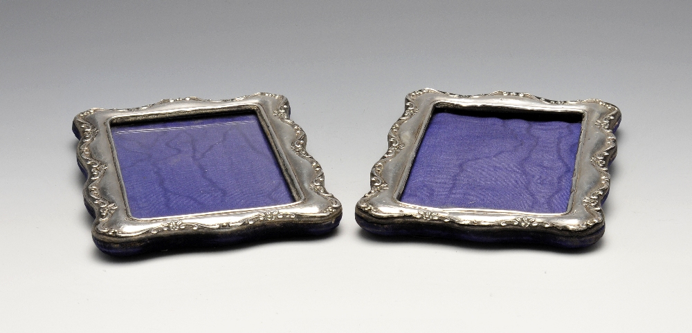 A pair of Edwardian silver mounted photograph frames, each of shaped rectangular form with a