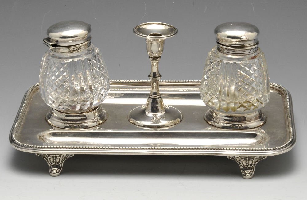 A late Victorian silver inkstand of rounded rectangular form with beaded rim and raised on four