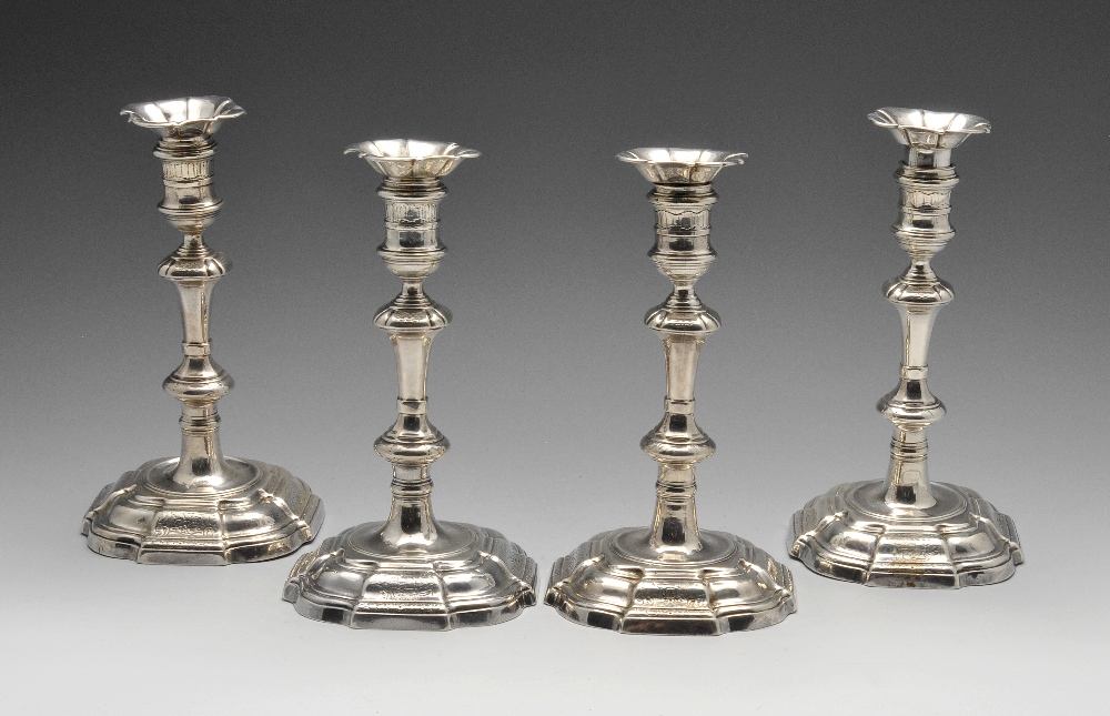 A set of four George II cast silver candlesticks, the octagonal fluted bases alternating with floral