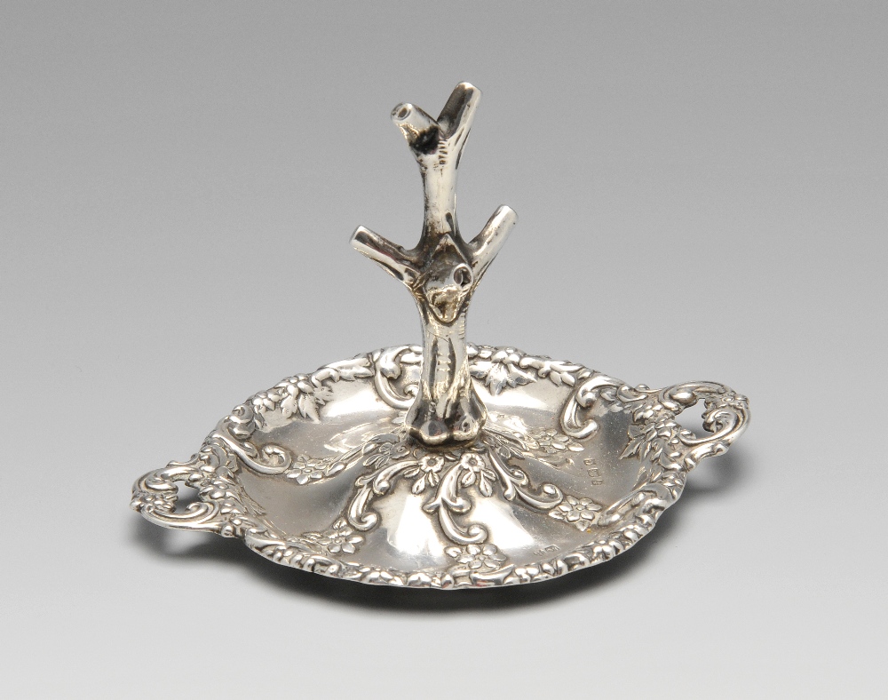 An Edwardian silver ring tree, the twin-handled circular form decorated with floral scrolls and