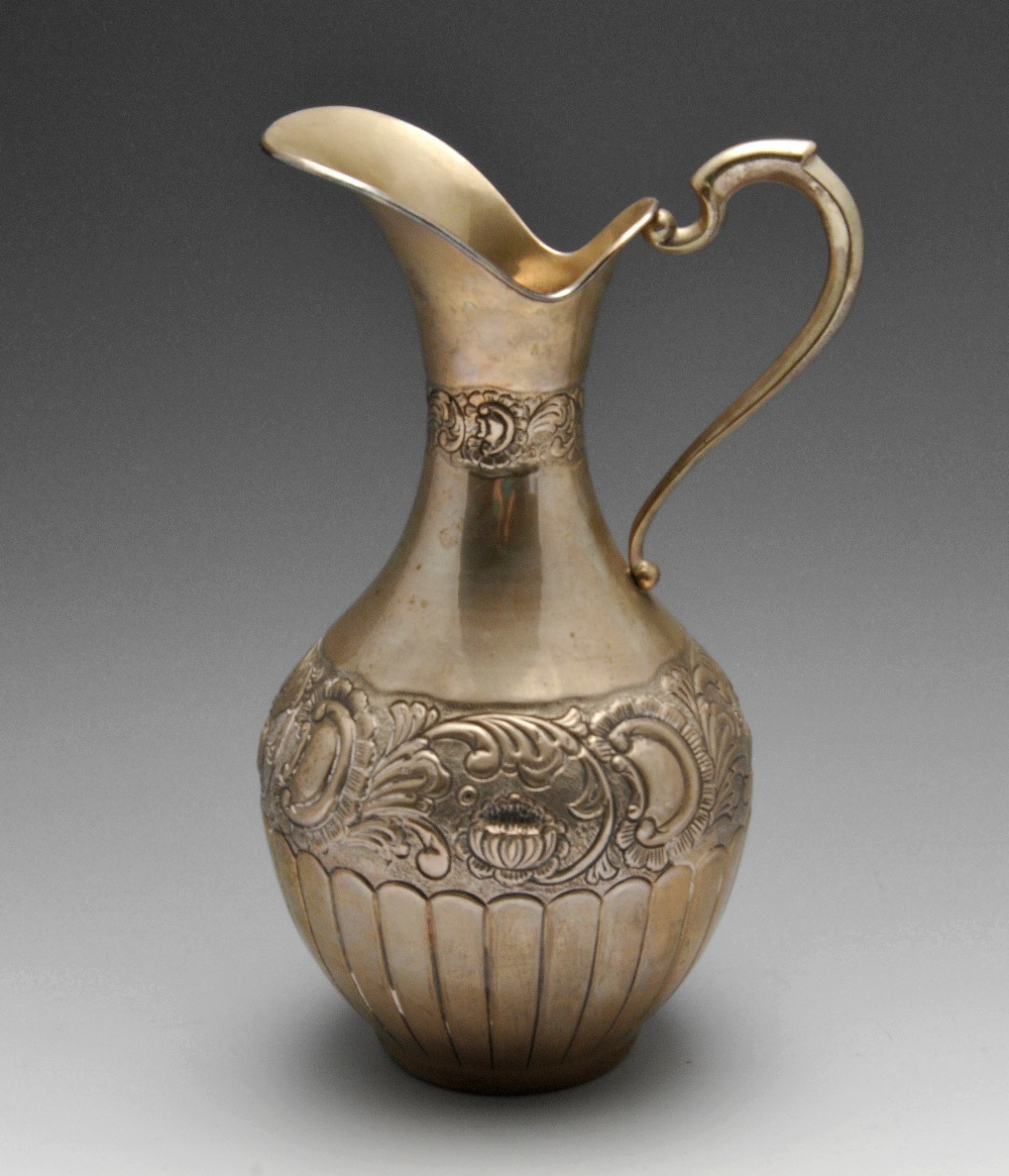 A Continental silver jug, of part fluted baluster form embossed with floral bands. Marked beneath