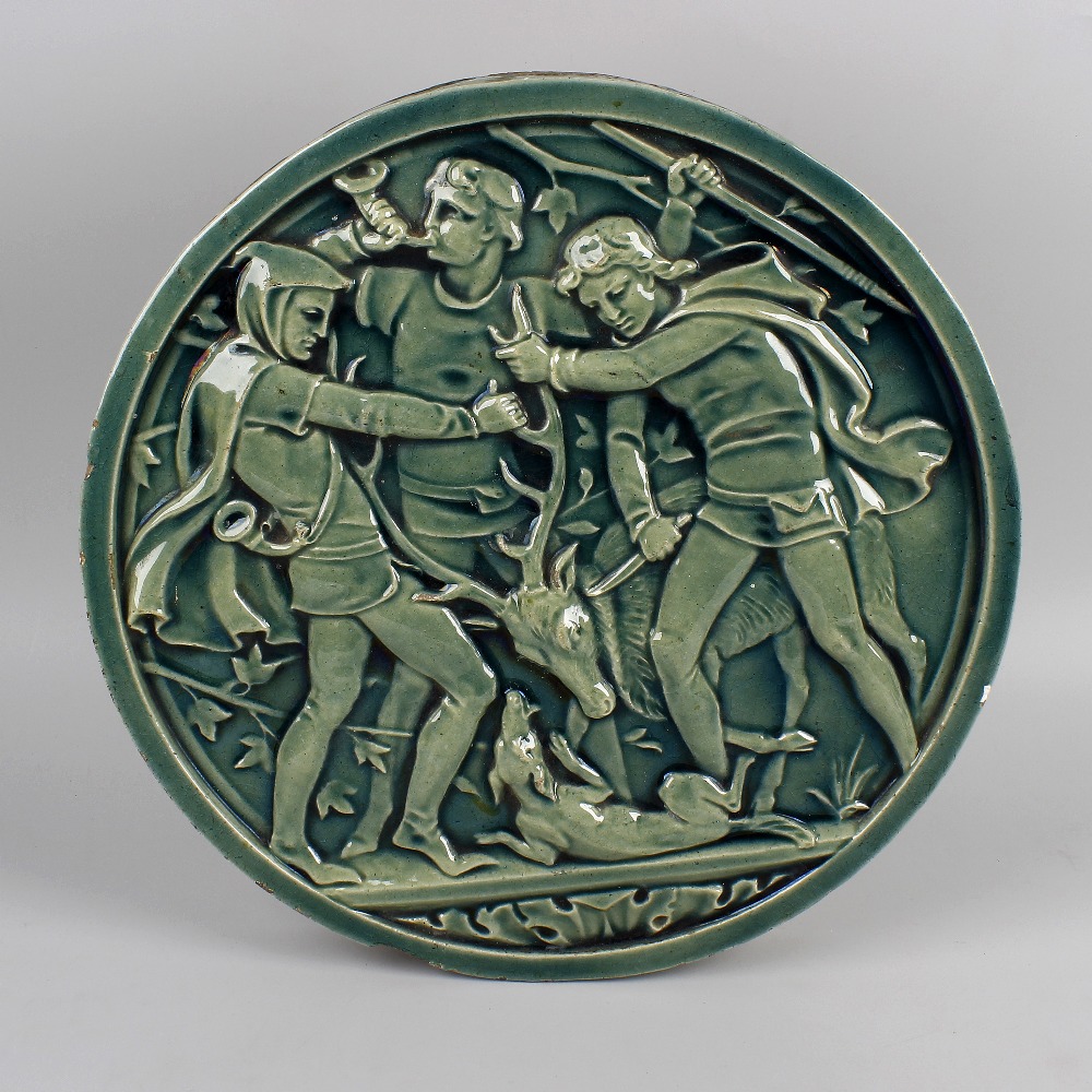 An Arts and Crafts pottery plaque. Of circular form, decorated with raised hunting scene of three