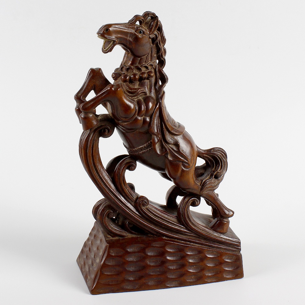 An unusual Oriental carved wooden figure. Modelled as a saddled horse galloping upon a wave, with