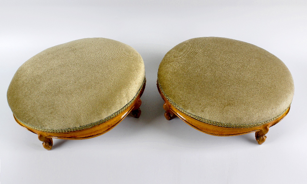 A pair of late Victorian walnut oval footstools. Each with sage green plush seat on four French