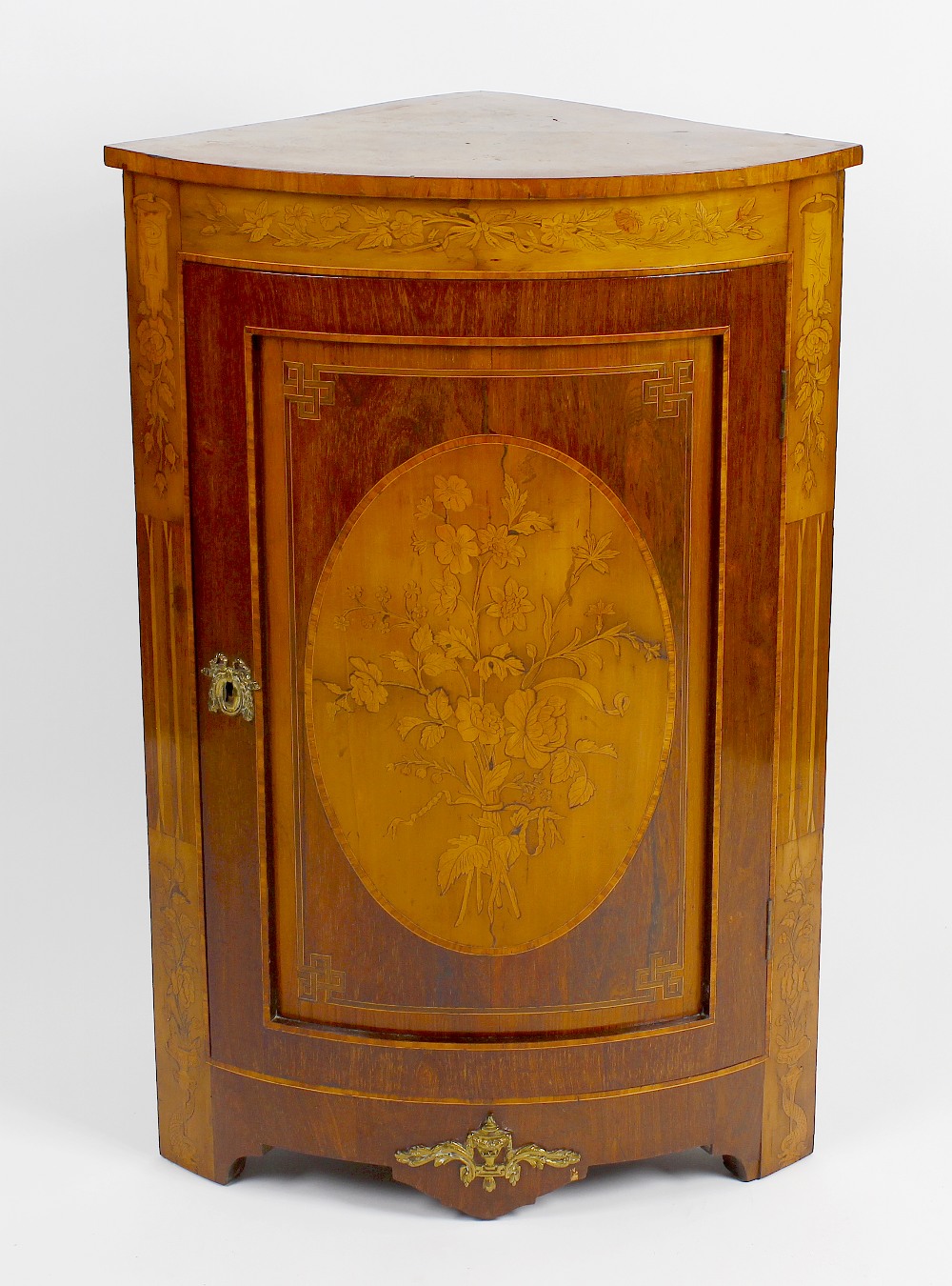 An early 20th century floor standing corner cabinet. The front with curved panelled door, inlaid