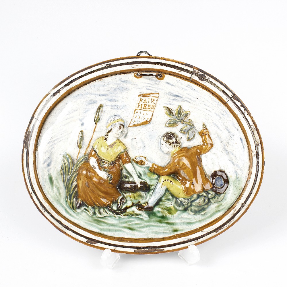 A late 18th century pearlware oval plaque. Depicting a couple seated within a landscape in high