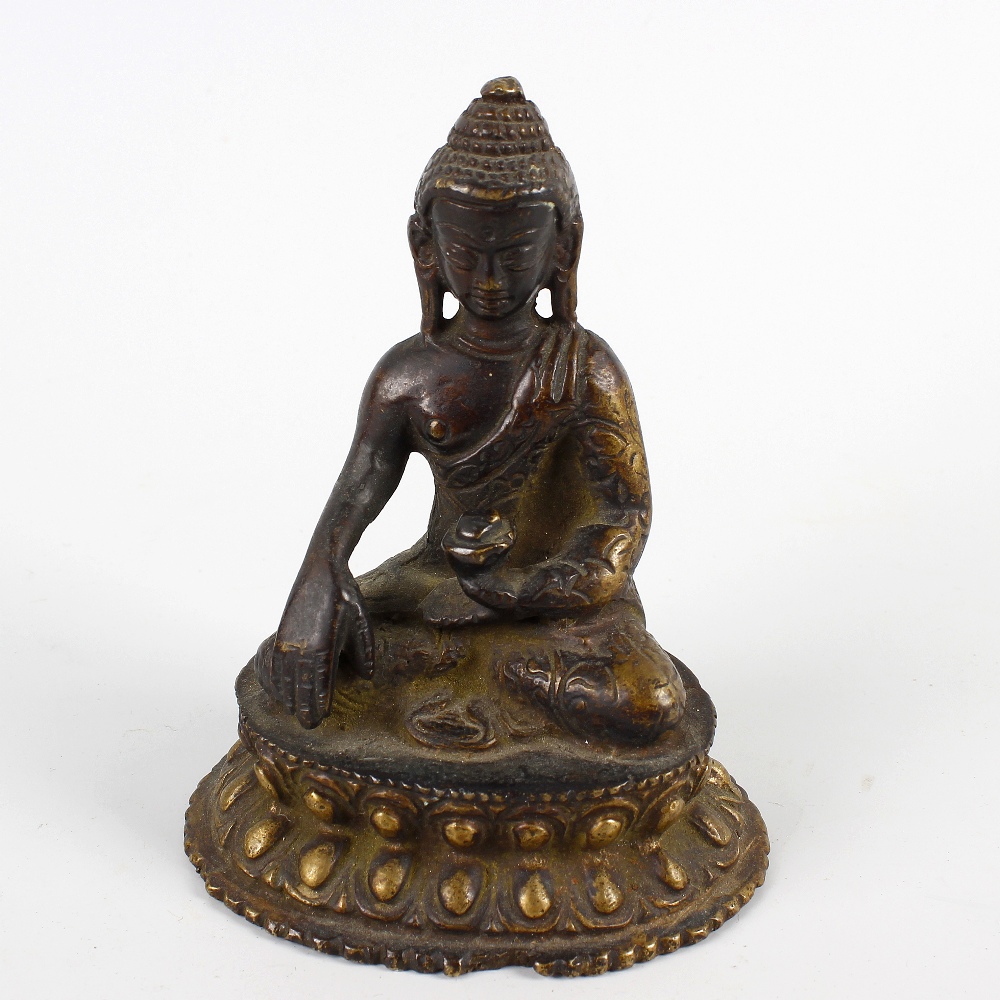 A South East Asian cast bronze figure of a Buddha. Modelled in seated Lotus position holding a