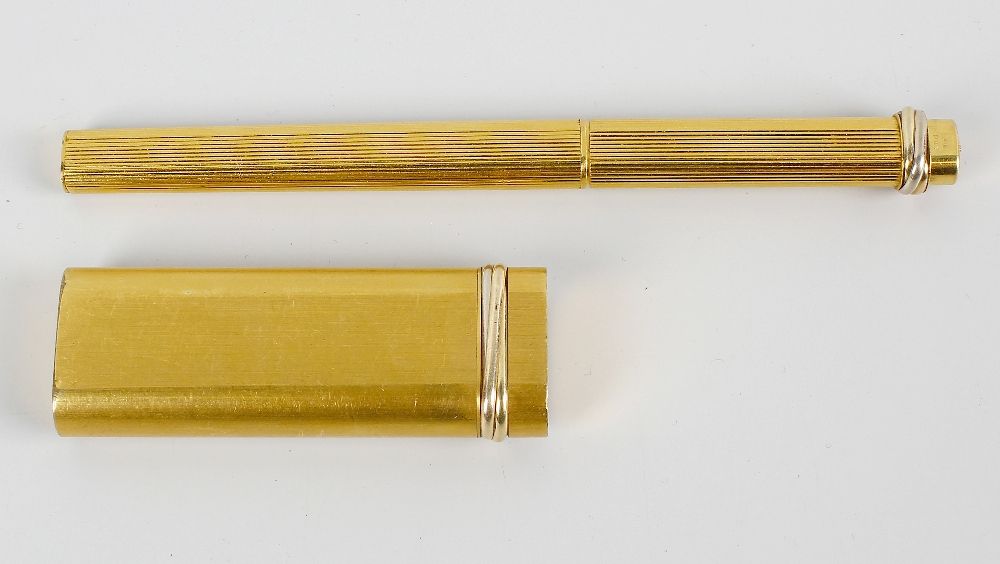 A gold plated Cartier ballpoint pen. Of oblong form having brushed surface to the whole and with