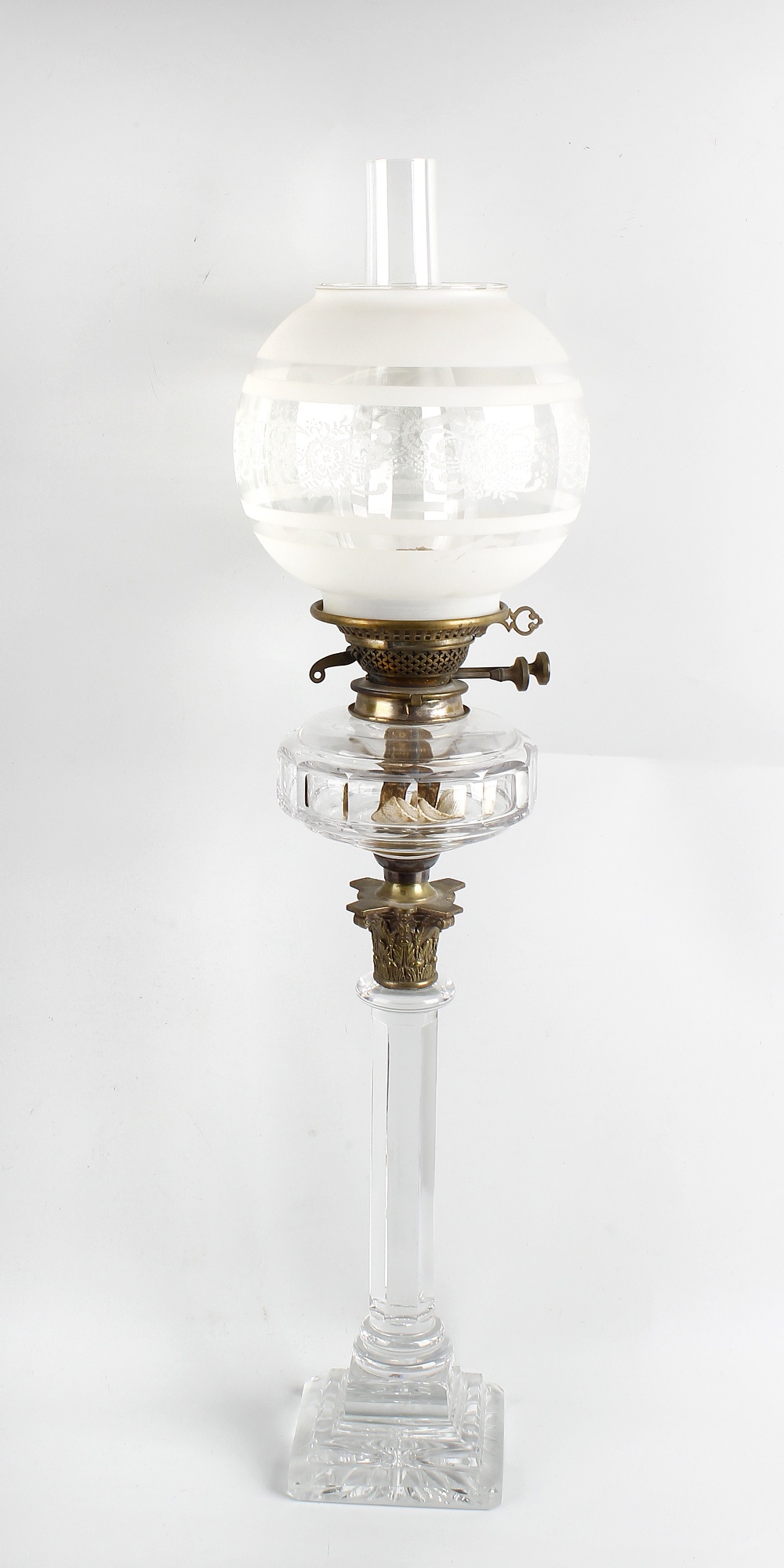 A glass paraffin lamp, with frosted spherical shaped shade over duplex burner, glass and brass