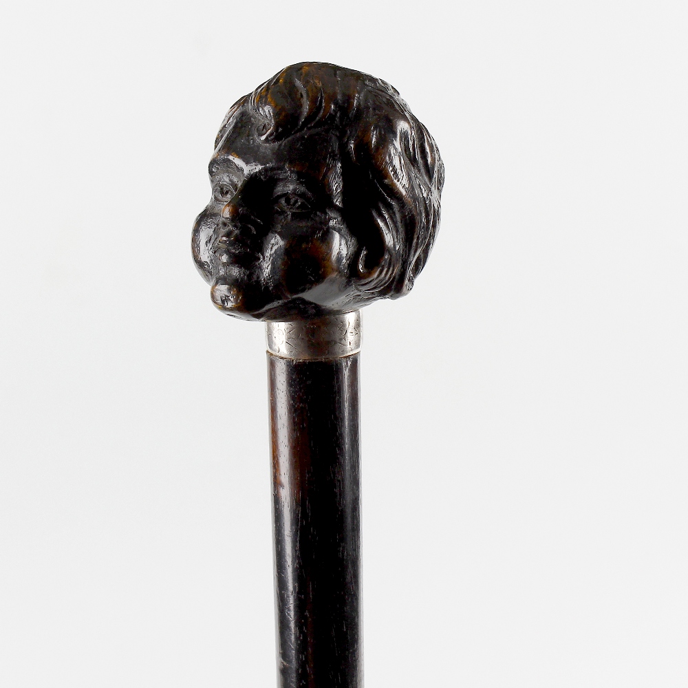 An unusual ebonised walking stick or cane. The handle carved as the head of a child, on engraved