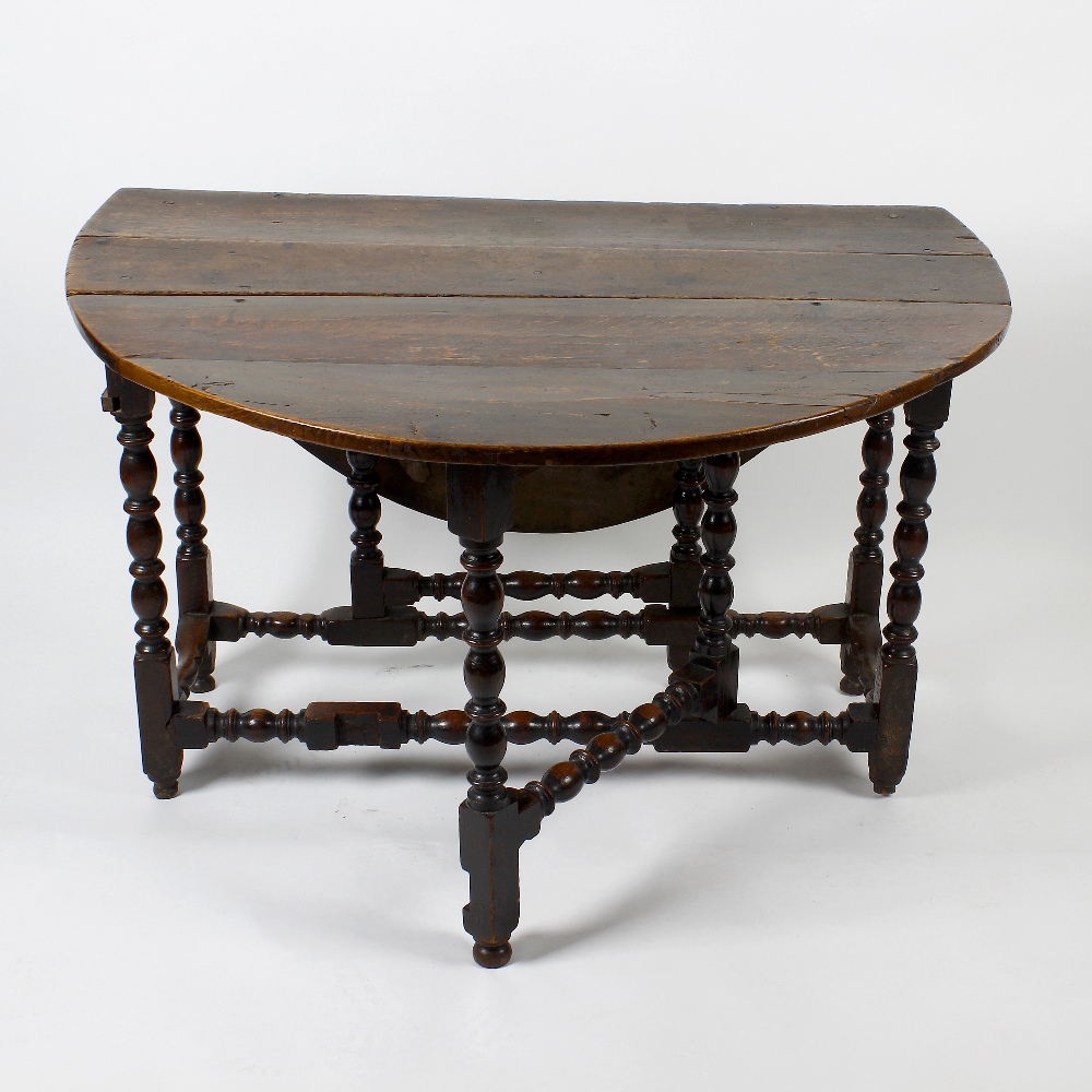 A late 17th century oak gateleg table. Having a two-plank top with oval flaps on bobbin- and ring-