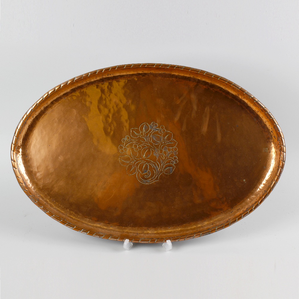 An Arts and Crafts oval copper dish by Hugh Wallis, the central panel, decorated with an engraved