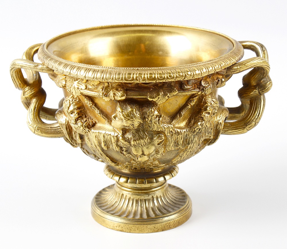 A 19th century small bronze Warwick vase. The relief cast Bacchanalian frieze above formal leaf