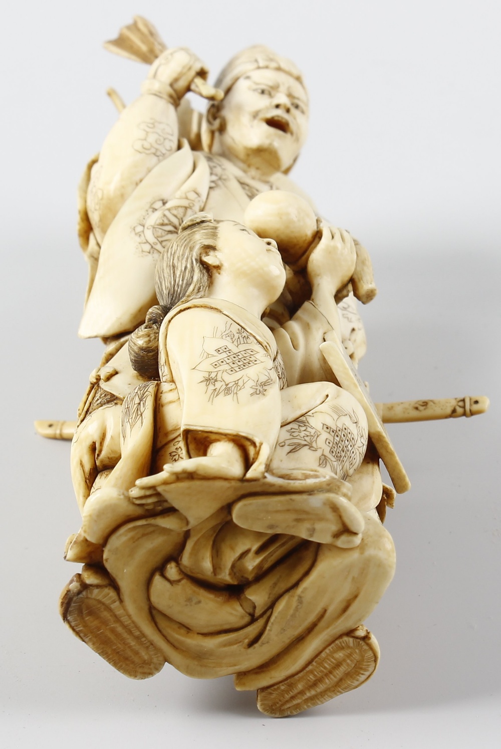 A 19th century carved ivory okimono, modelled as a male laden with sword and other tools, a female - Image 2 of 2