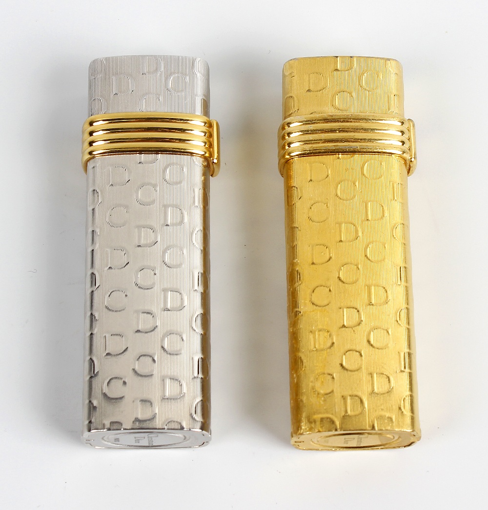 A pair of lighters by Christian Dior. Comprising a white gold plated example stamped Plaque OR G,