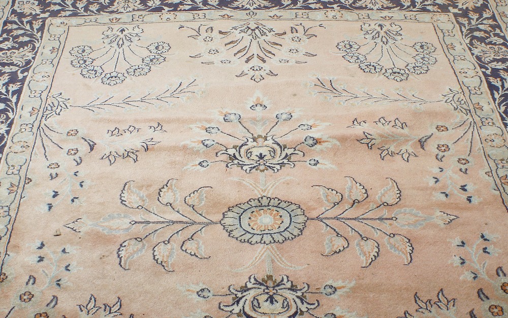 A carpet or rug. The central field sparsely decorated with floral motifs upon a pale pink ground,