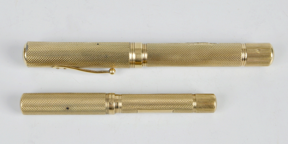 Two Watermans Ideal 9ct gold fountain pens, each having an engine turned cylindrical barrel with