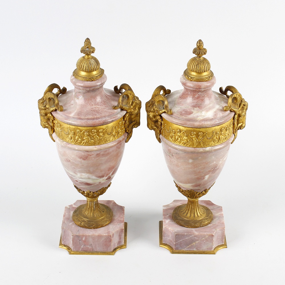 A pair of ormolu-mounted pink marble urns. Each of neoclassical form with cast domed finial over a