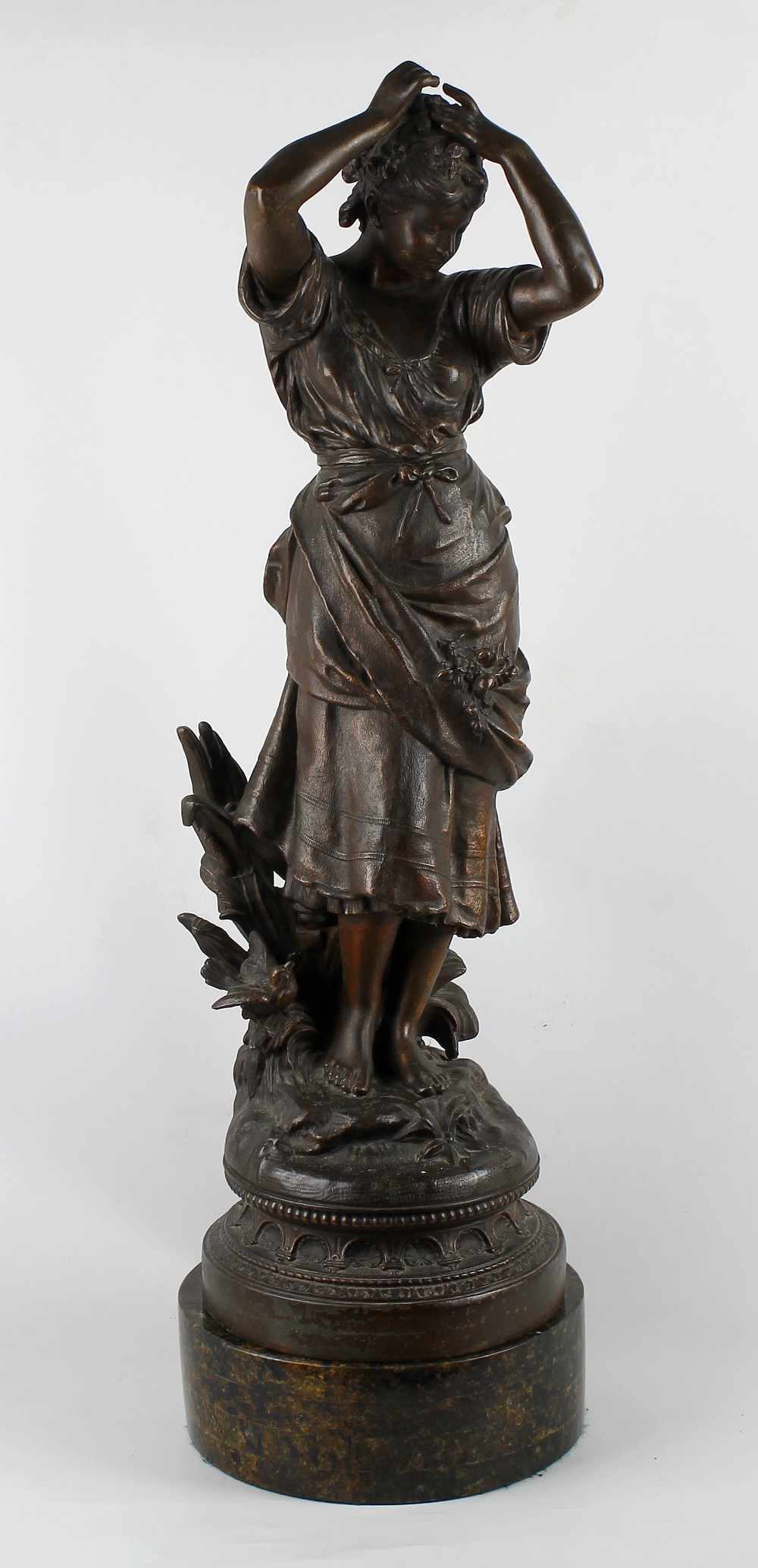 A large spelter figure Circa 1900, modelled as a maiden arranging flowers in her hair, cast 'M.M.S
