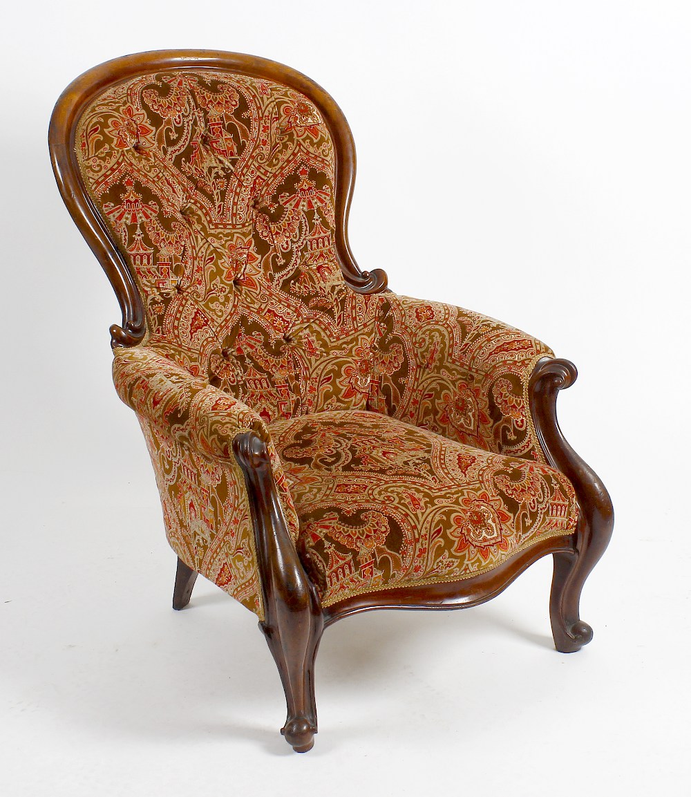 A mid 19th century mahogany-framed spoon-back easy chair. The deep-buttoned spoon back, scroll