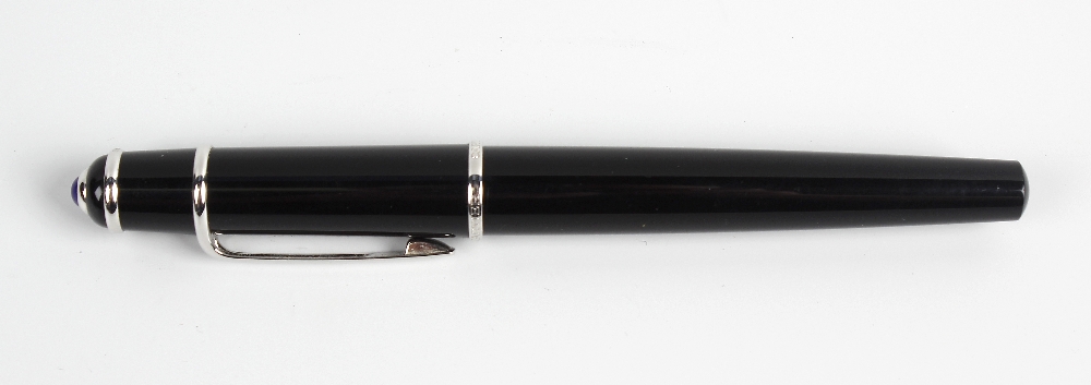 A Cartier Diabolo fountain pen. The black resin body having silvered banding and clip, with blue gem