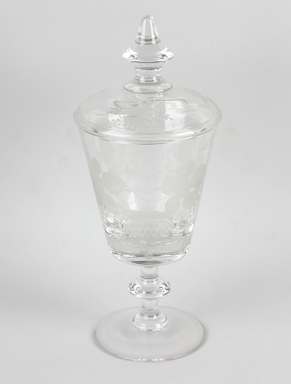 An etched glass pedestal vase and cover. The tapering vase etched with grapevines, raised upon a