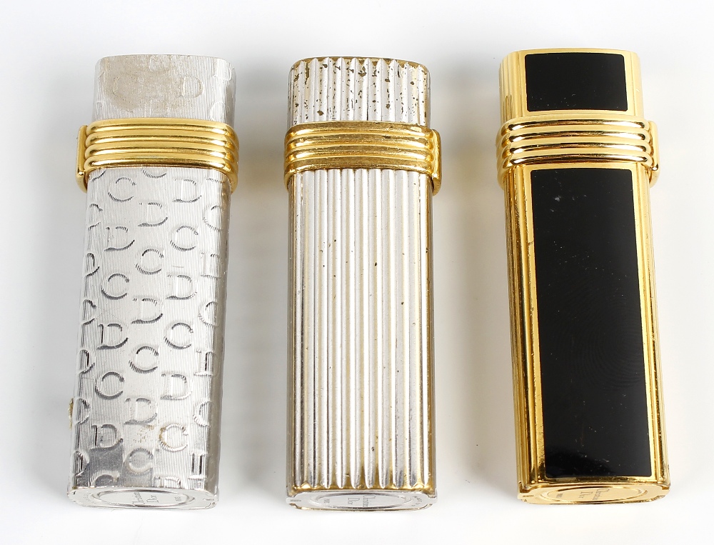 A selection of three Christian Dior lighters. Comprising two white gold plated examples stamped