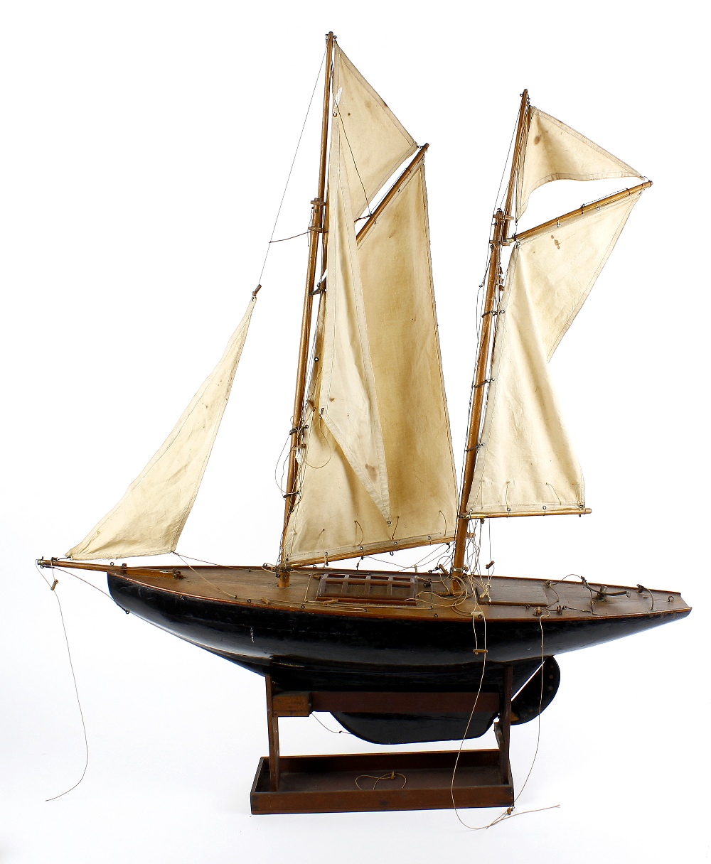 A wooden plank on frame model yacht, the twin masts with stitched cloth sails above a simulated