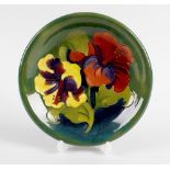 A Walter Moorcroft pottery dish. Decorated in the Hibiscus pattern on glazed green ground, with