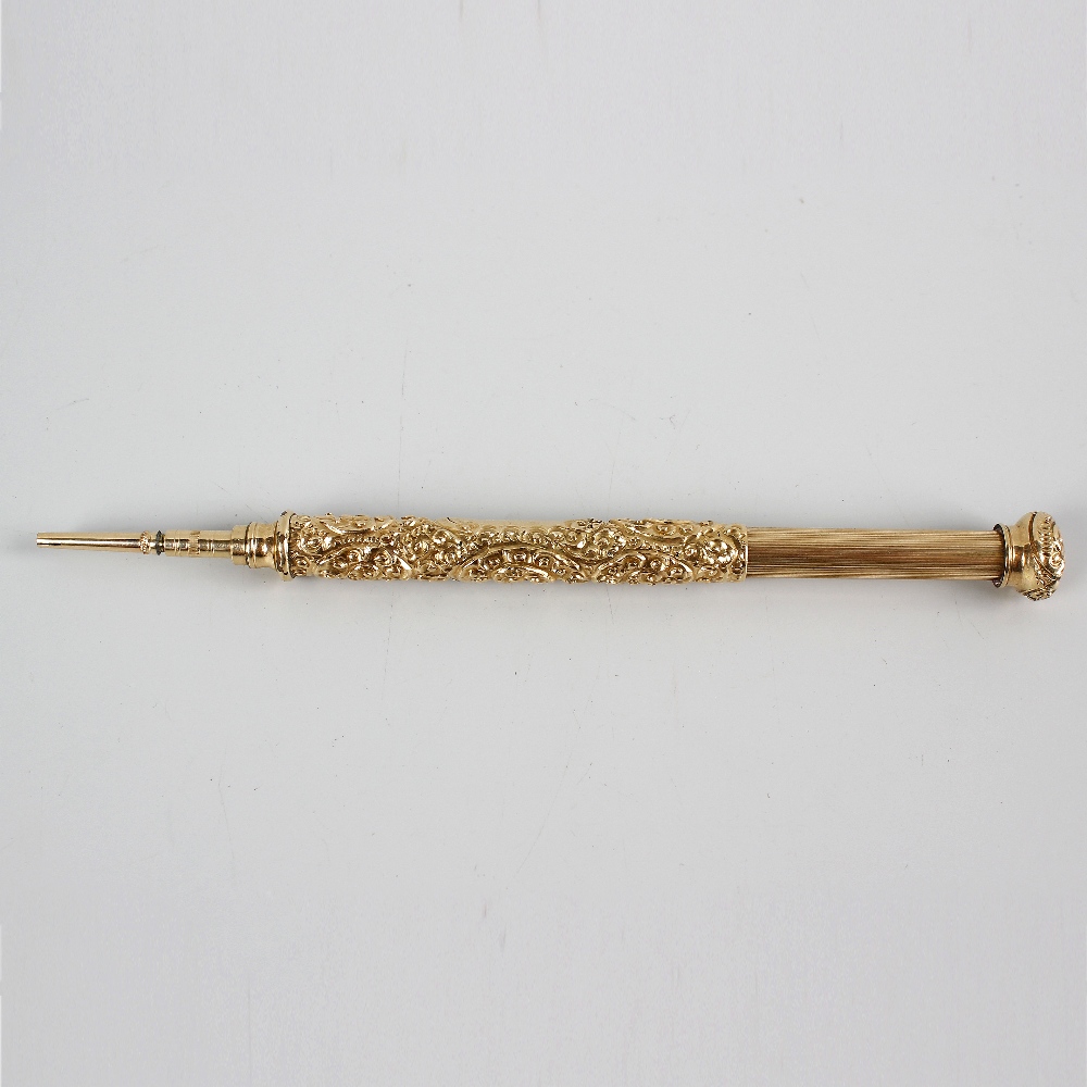 A yellow metal retractable pencil. The barrel decorated with high relief foliate scrollwork and