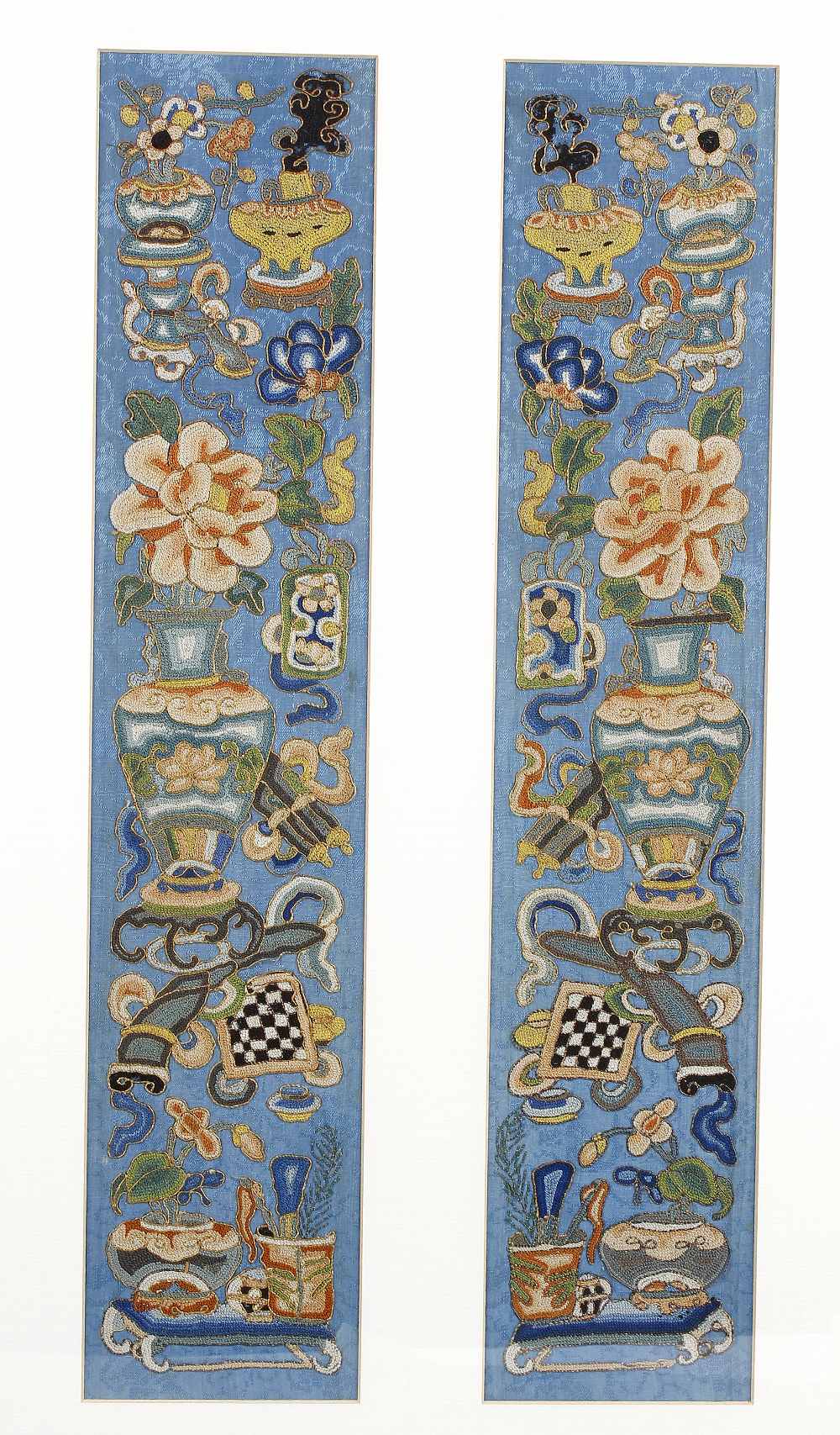 A pair of Chinese silk panels, of near symmetrical design, embroidered with vases of flowers,