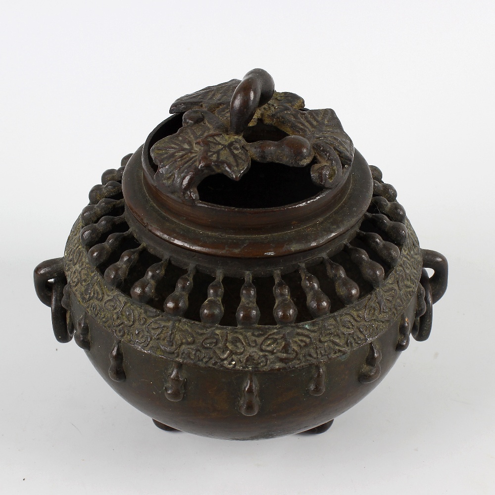An Oriental bronze koro or incense burner and cover. Of spherical form with pierced domed foliate