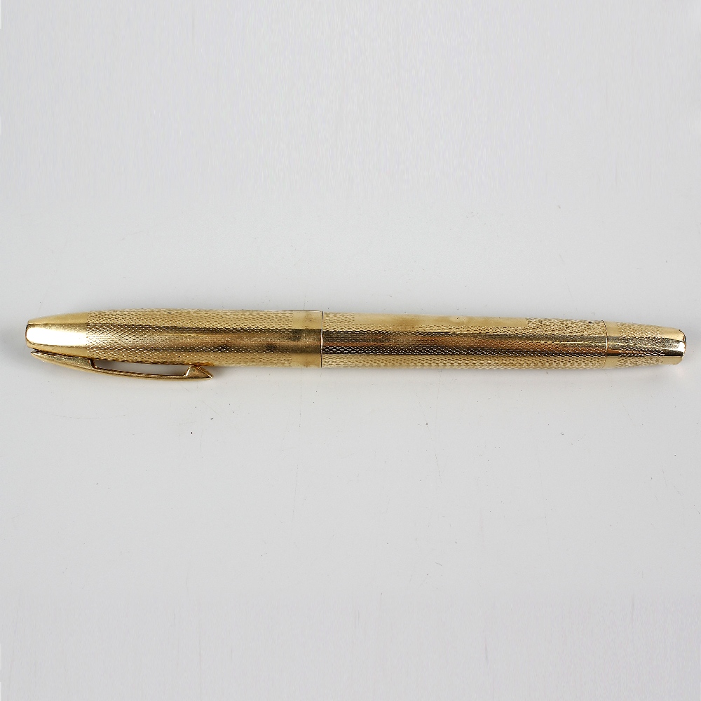 A 9ct gold Sheaffer fountain pen. Having 14k gold nib, the engine turned body with vacant