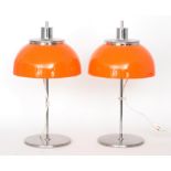 Harvey Guzzini - A pair of table lamps with adjustable orange domed shades over a chromed steel