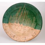 A large contemporary studio pottery shallow bowl decorated with a green glaze with white dribble