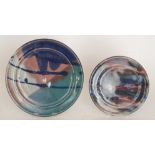 Fourteen varying sized studio pottery plates each decorated with brightly coloured glazes trails