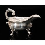 A George II hallmarked silver sauce boat of plain form raised on three lion mask pad feet,