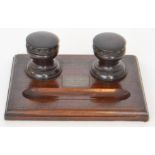 An early 20th Century oak desk stand with castellated turned inkwells with ceramic liners and inset