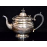 A George V hallmarked silver teapot of squat circular form with beed and reel rim,