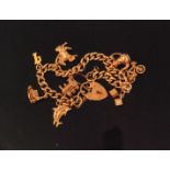 A 9ct curb link charm bracelet with padlock fastener and eight attached 9ct charms,