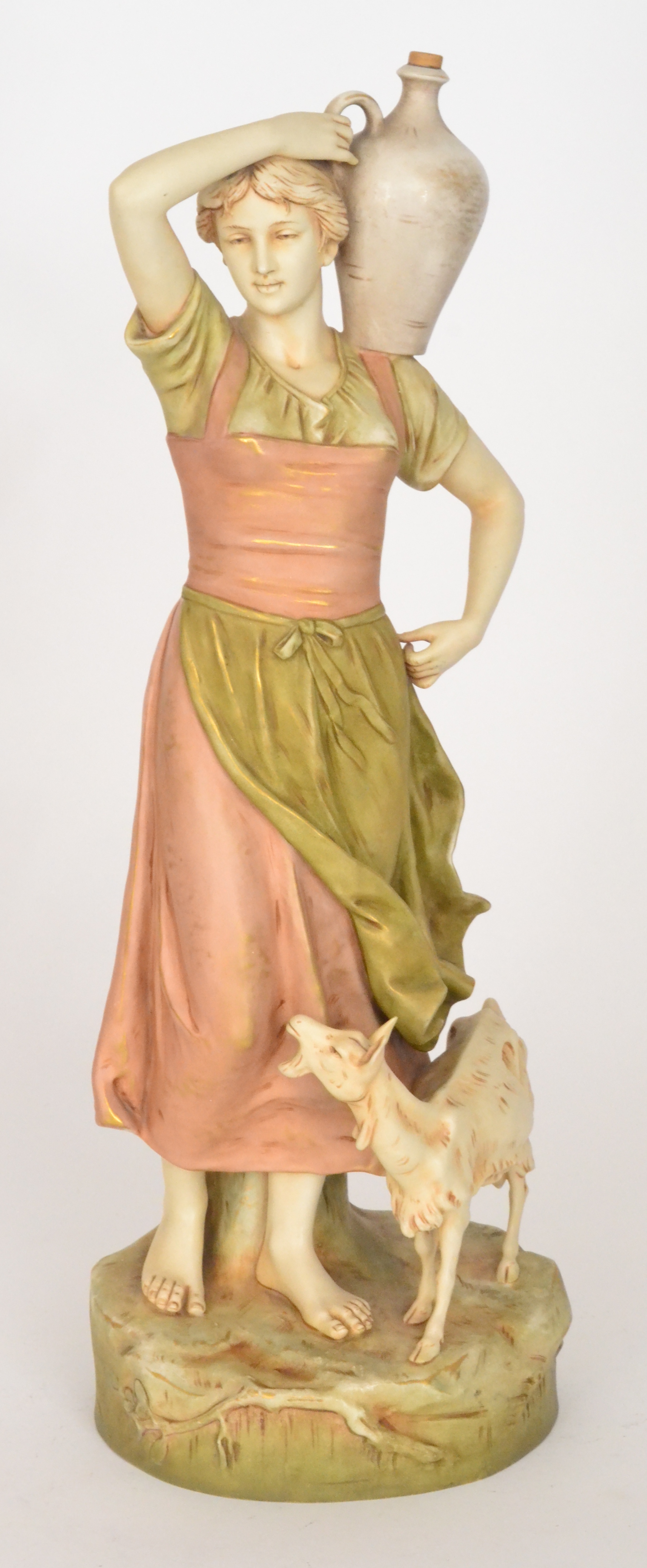 A large Royal Dux Bohemia figure of a lady dressed in green and soft red robes holding an urn to