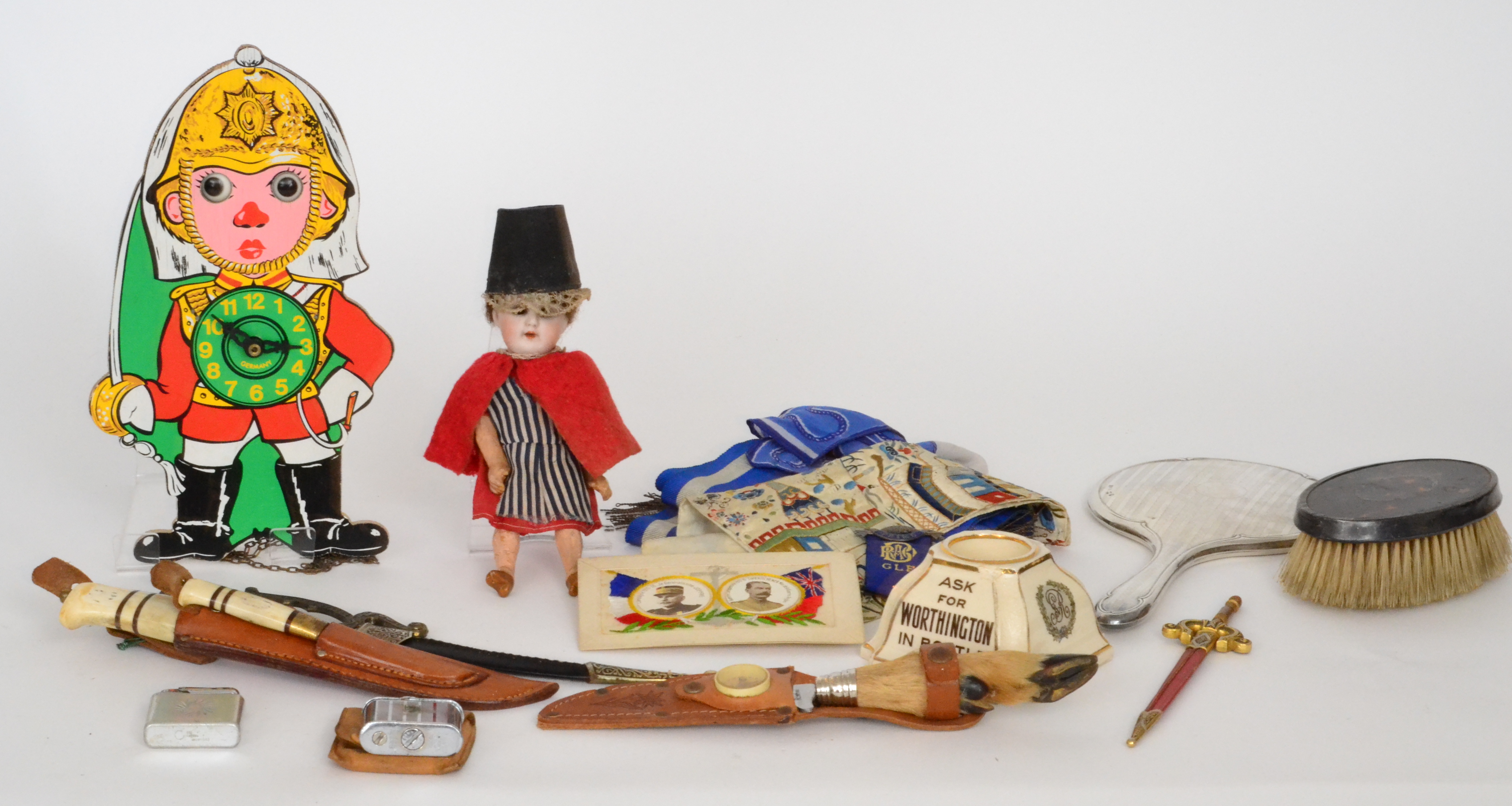 A small German bisque head doll in Welsh costume together with a novelty painted wall clock of a