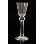 An 18th Century drinking glass circa 1730 with a round funnel bowl above a plain teared stem with