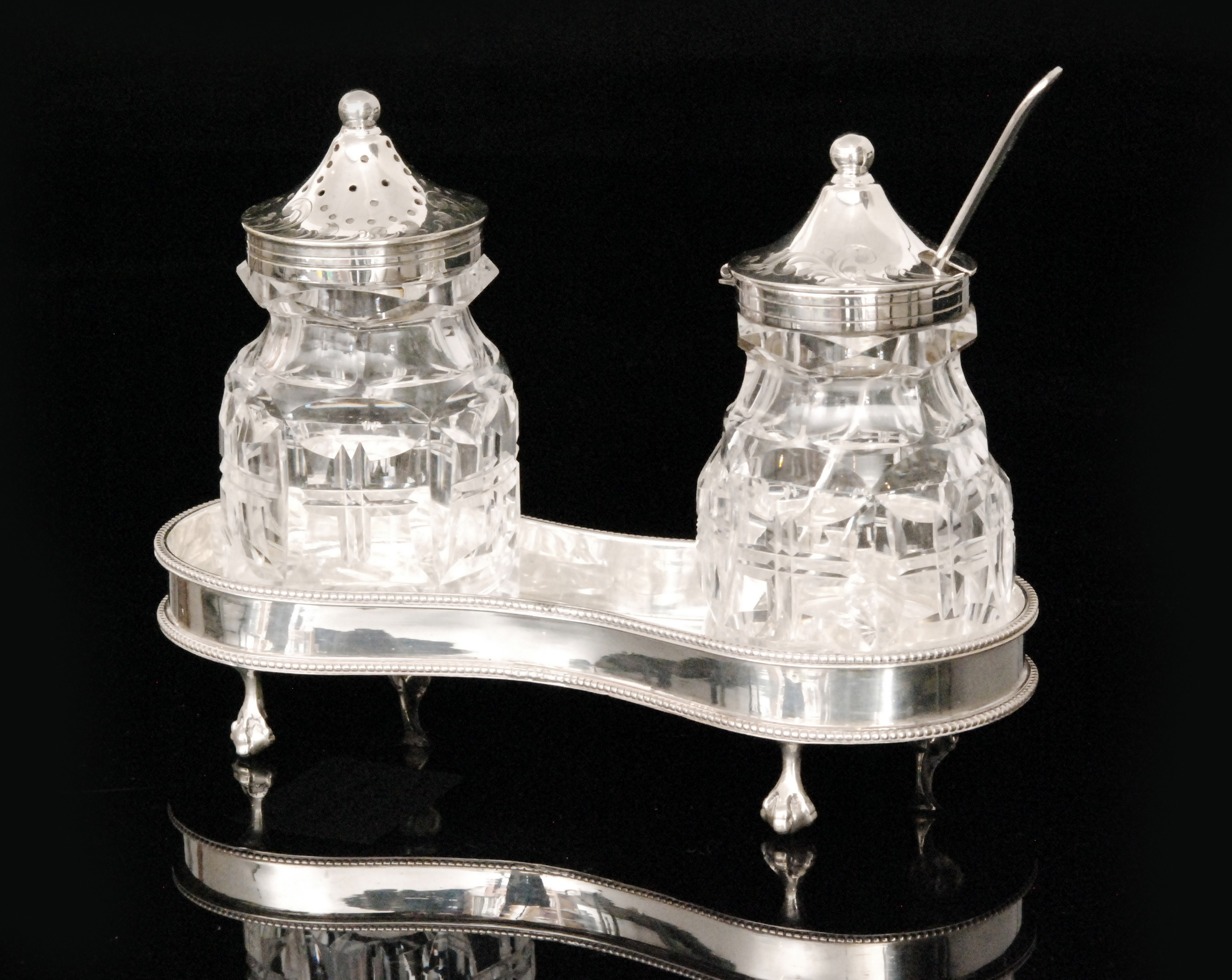 A George III hallmarked two bottle condiment stand of shaped outline with beaded borders,