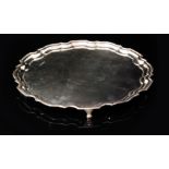 A mid 20th Century hallmarked silver circular salver with pie crust border and raised on three